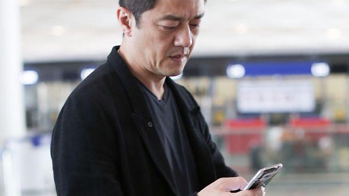 李亚鹏西装配球鞋休闲帅气 低头皱眉看手机